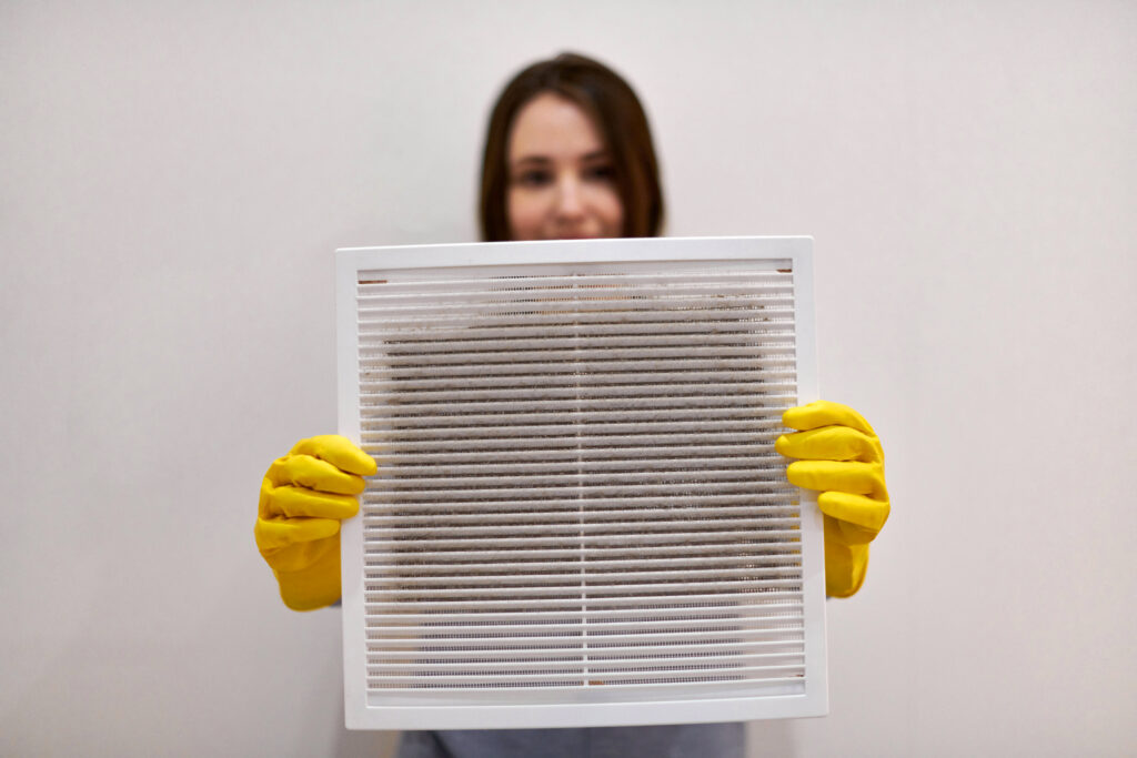 Kvinna som håller i ett smutsigt filter med gula plasthandskar